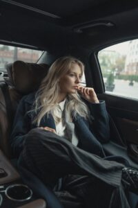 A thoughtful businesswoman sits in a luxurious car, pondering during a ride.